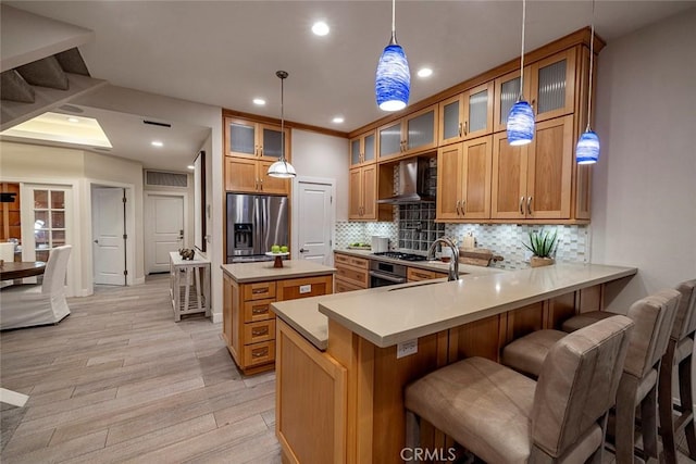 kitchen with kitchen peninsula, light hardwood / wood-style flooring, wall chimney exhaust hood, decorative backsplash, and stainless steel fridge with ice dispenser