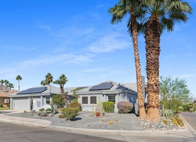 view of front of property featuring solar panels and a garage