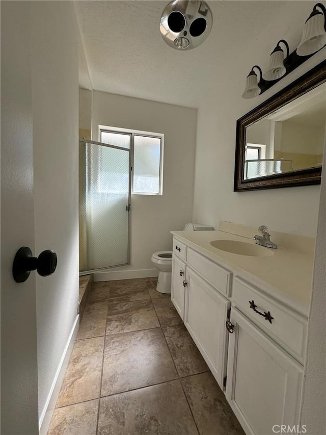 bathroom featuring tile patterned floors, vanity, toilet, and a shower with door