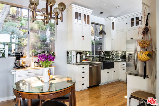 kitchen with backsplash, stainless steel appliances, sink, decorative light fixtures, and white cabinetry