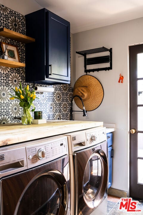 laundry room featuring washing machine and clothes dryer and cabinets