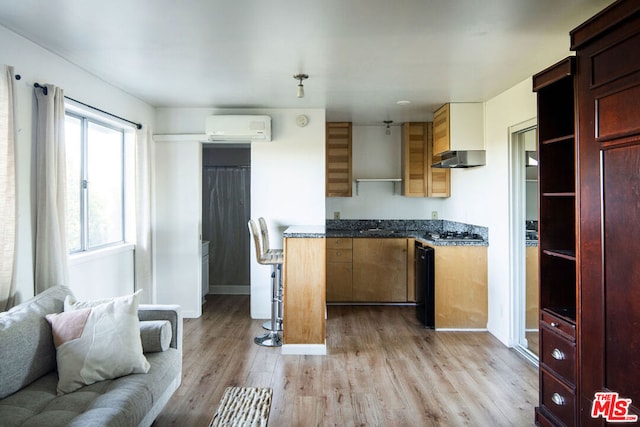 kitchen with a wall unit AC, dishwasher, and light wood-type flooring