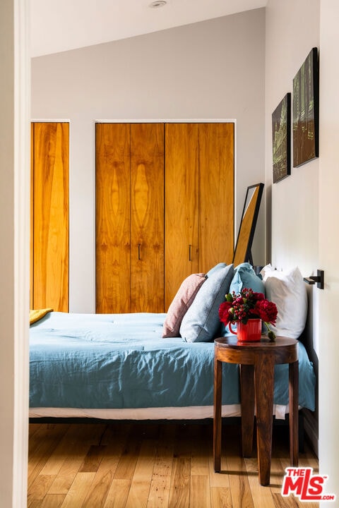 bedroom featuring light wood-type flooring and lofted ceiling