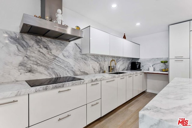 kitchen with black electric stovetop, sink, light hardwood / wood-style flooring, white cabinets, and range hood