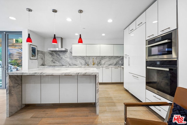 kitchen with backsplash, light stone counters, pendant lighting, light hardwood / wood-style floors, and white cabinetry