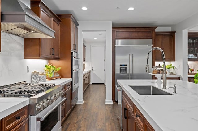 kitchen with light stone countertops, dark hardwood / wood-style flooring, sink, custom range hood, and high quality appliances