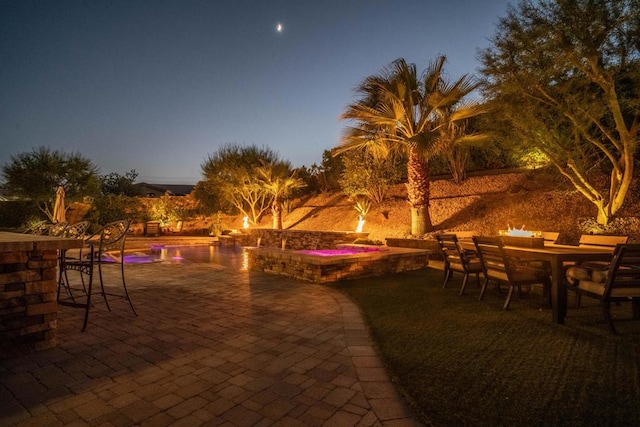 patio terrace at dusk with a pool with hot tub and exterior bar