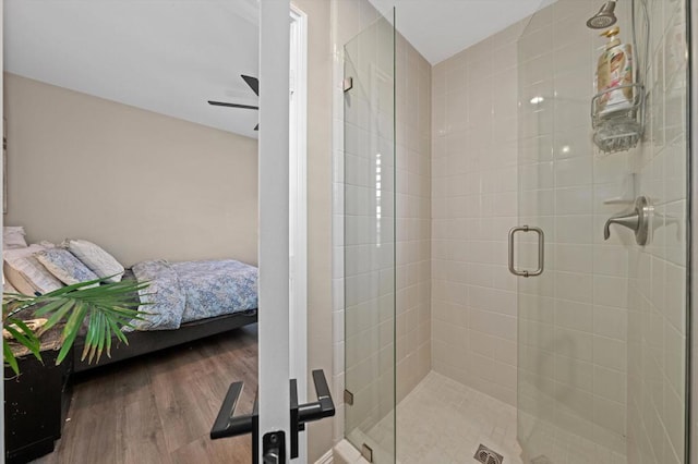 bathroom featuring hardwood / wood-style flooring, a shower with shower door, and ceiling fan