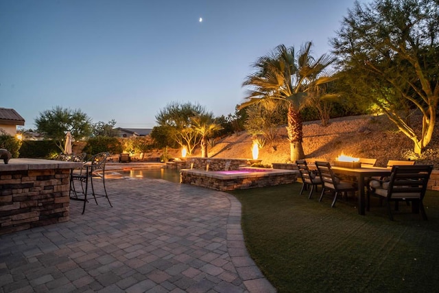 patio terrace at dusk with a swimming pool with hot tub and an outdoor bar