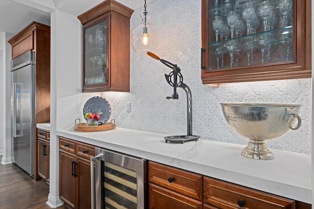 bar with backsplash, decorative light fixtures, dark wood-type flooring, wine cooler, and stainless steel built in refrigerator