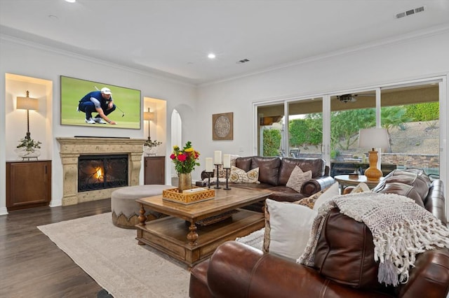 living room featuring dark wood-type flooring, crown molding, and a fireplace