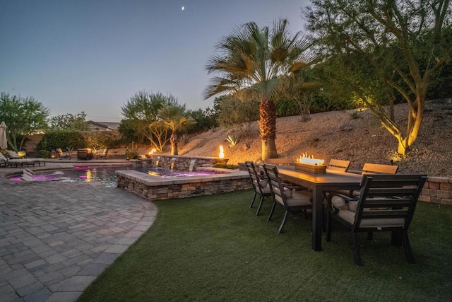 patio terrace at dusk featuring a lawn