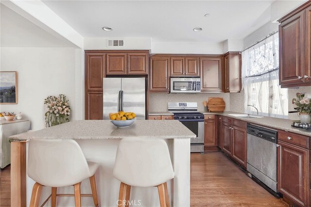 kitchen featuring a center island, a kitchen bar, wood-type flooring, and stainless steel appliances