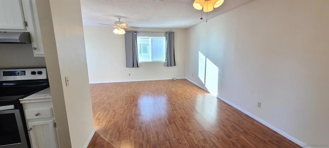 interior space with a textured ceiling, ceiling fan, and light hardwood / wood-style flooring