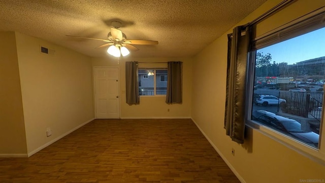 empty room with a textured ceiling, dark hardwood / wood-style flooring, and ceiling fan