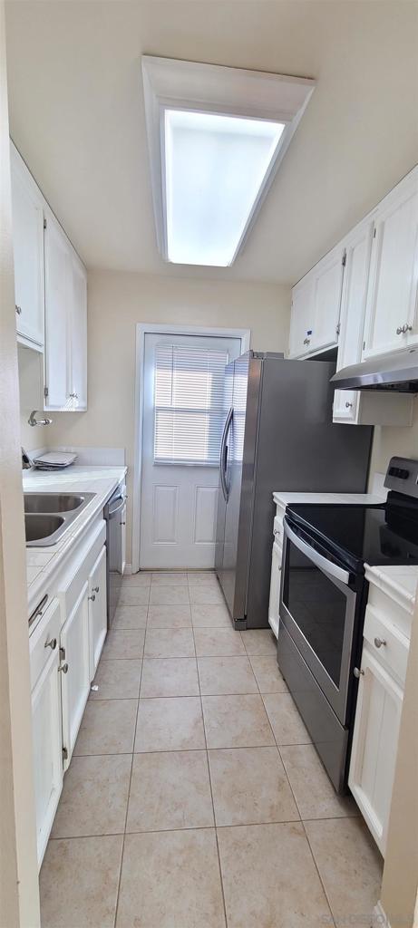 kitchen with light tile patterned floors, white cabinets, dishwasher, and stainless steel electric range oven