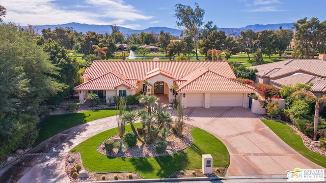 mediterranean / spanish house with a mountain view, a garage, and a front yard