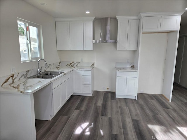 kitchen with wall chimney exhaust hood, dark hardwood / wood-style flooring, white cabinetry, and sink