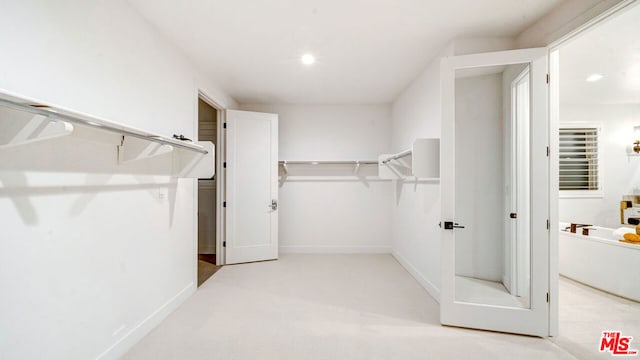 walk in closet featuring light colored carpet