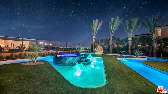 pool at twilight featuring pool water feature, an in ground hot tub, and a yard