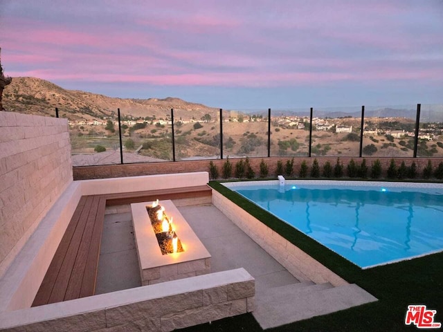 pool at dusk featuring an outdoor fire pit and a mountain view