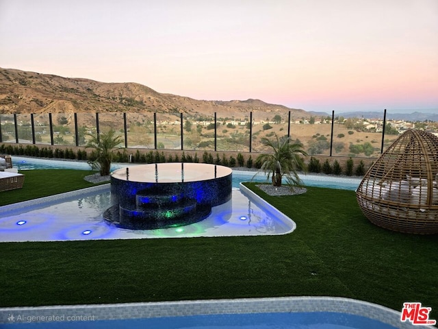 pool at dusk featuring a lawn and a mountain view