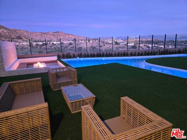 pool at dusk with a mountain view and an outdoor fire pit