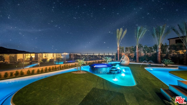 pool at twilight featuring an in ground hot tub