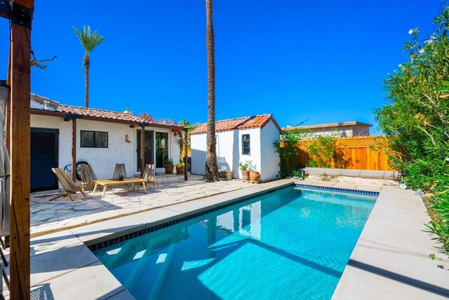 view of pool featuring a patio and a storage shed