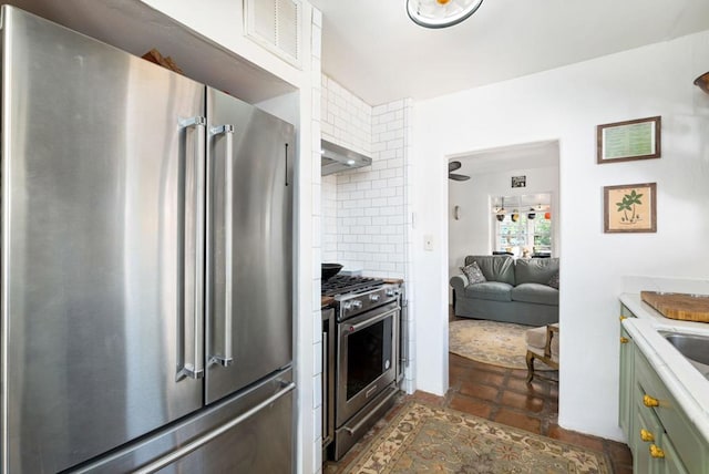 kitchen featuring tasteful backsplash, high quality appliances, exhaust hood, and green cabinetry