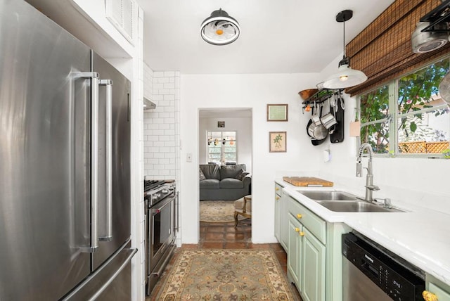 kitchen featuring pendant lighting, premium appliances, green cabinets, and sink