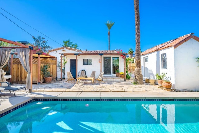 back of property with a fenced in pool, a patio, and an outdoor structure