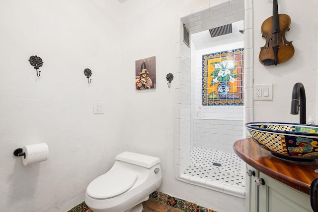 bathroom featuring vanity, toilet, and tiled shower