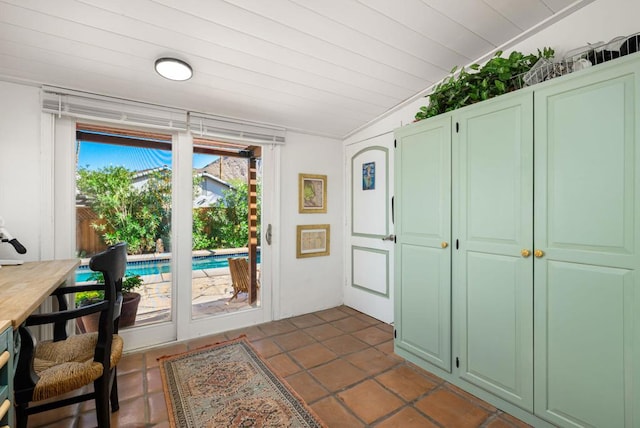 doorway with dark tile patterned flooring, lofted ceiling, and wooden ceiling