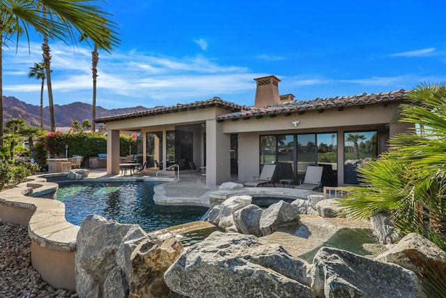 view of swimming pool with a patio area, a mountain view, and a hot tub