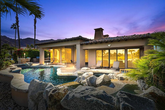 pool at dusk featuring a mountain view and a patio