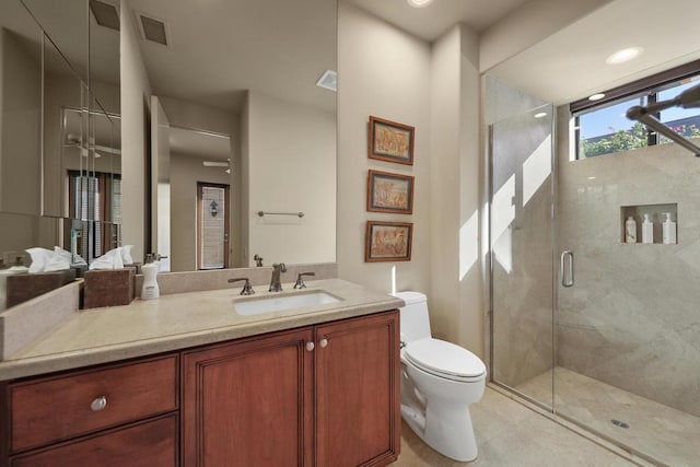 bathroom with tile patterned flooring, a shower with door, vanity, and toilet