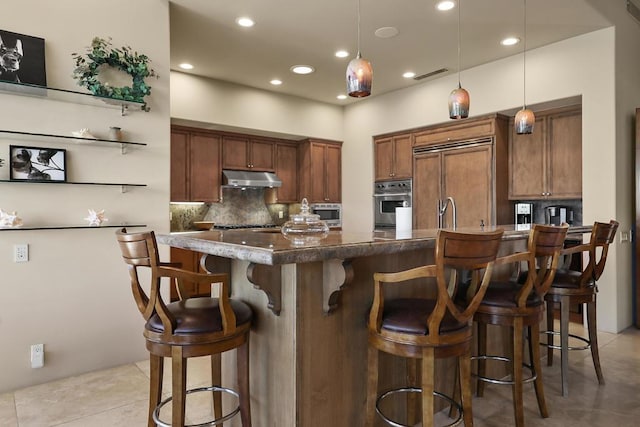 kitchen with a breakfast bar, built in appliances, hanging light fixtures, and backsplash