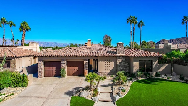 mediterranean / spanish house featuring a mountain view, a garage, and a front lawn