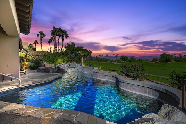 pool at dusk featuring pool water feature and a patio