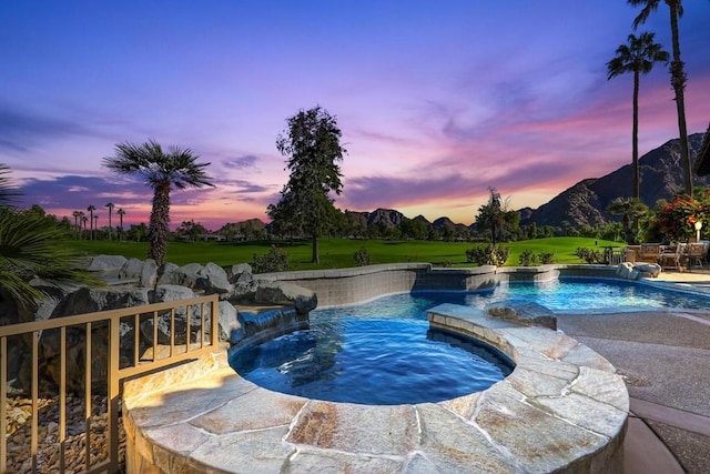 pool at dusk featuring an in ground hot tub, a mountain view, and pool water feature