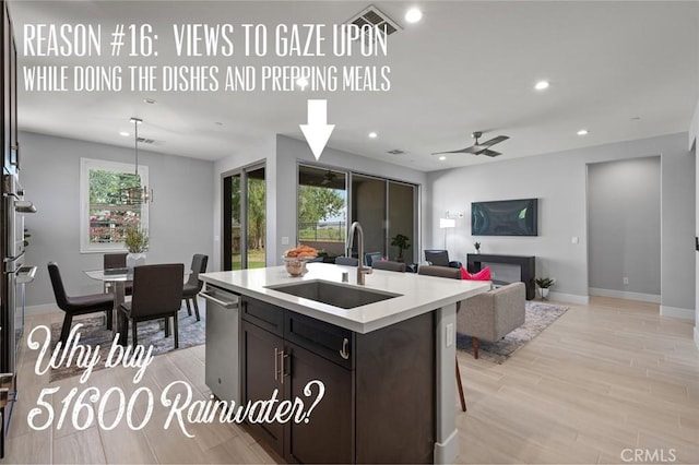 kitchen with a wealth of natural light, sink, light hardwood / wood-style floors, and a center island with sink