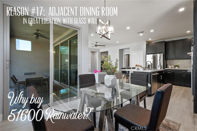 tiled dining room with ceiling fan with notable chandelier and sink