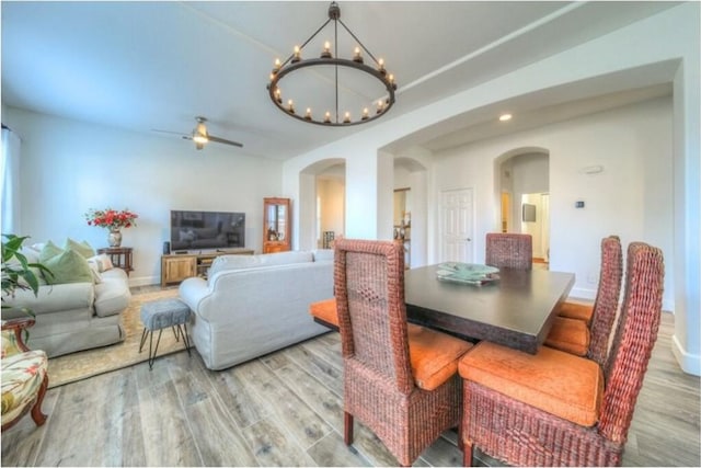 dining area with light hardwood / wood-style floors and ceiling fan with notable chandelier