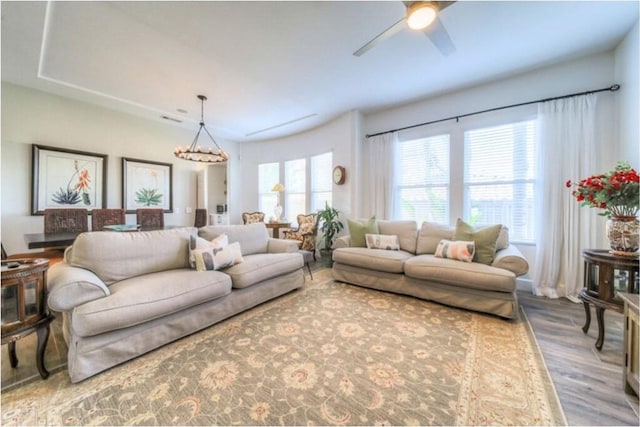 living room with hardwood / wood-style flooring and ceiling fan with notable chandelier