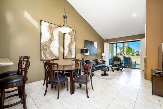 tiled dining space featuring high vaulted ceiling