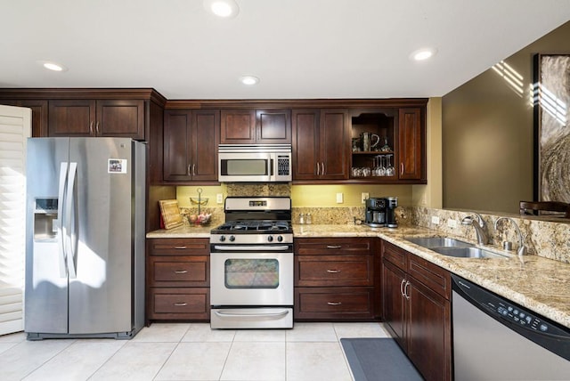 kitchen with light stone countertops, sink, stainless steel appliances, dark brown cabinets, and light tile patterned flooring