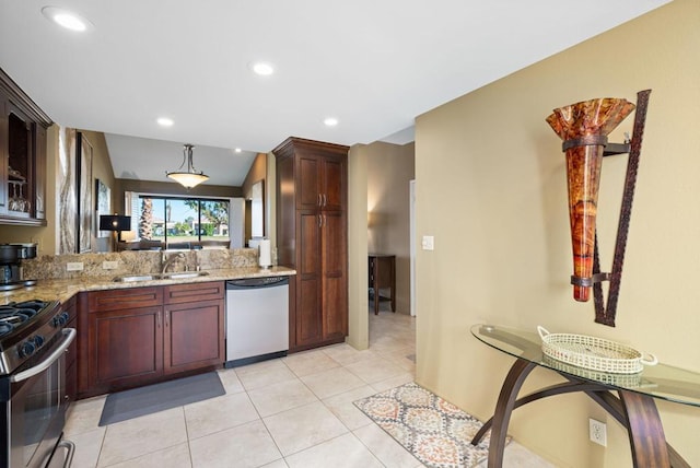 kitchen with sink, vaulted ceiling, light stone countertops, light tile patterned floors, and stainless steel appliances