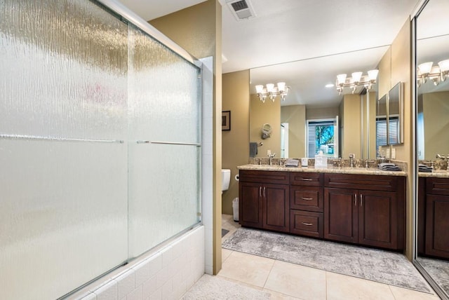 full bathroom with vanity, an inviting chandelier, enclosed tub / shower combo, tile patterned flooring, and toilet