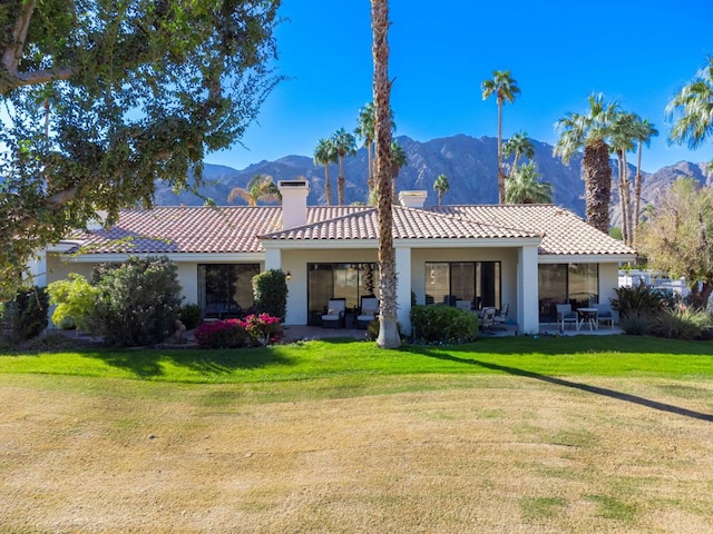 rear view of property with a mountain view, a patio, and a lawn